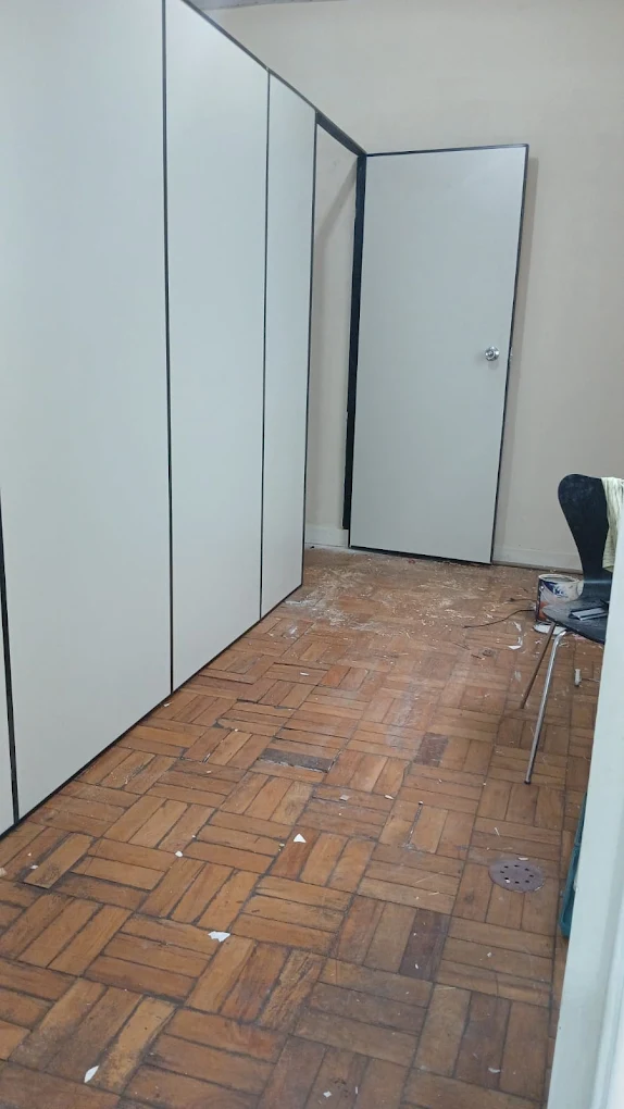 Divisória em painéis claros com porta, instalada em uma sala